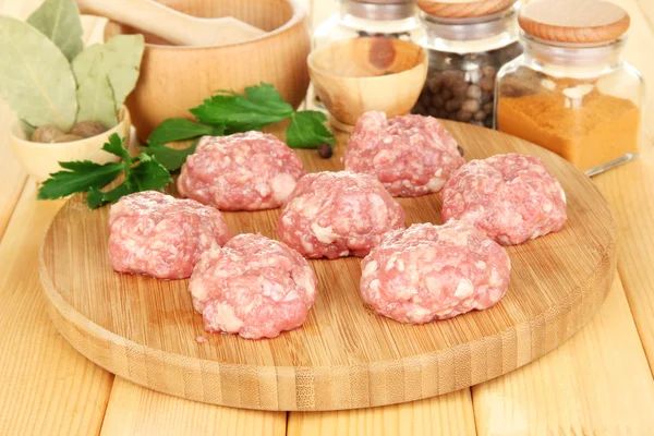 Raw meatballs with spices on wooden table — Stock Photo, Image