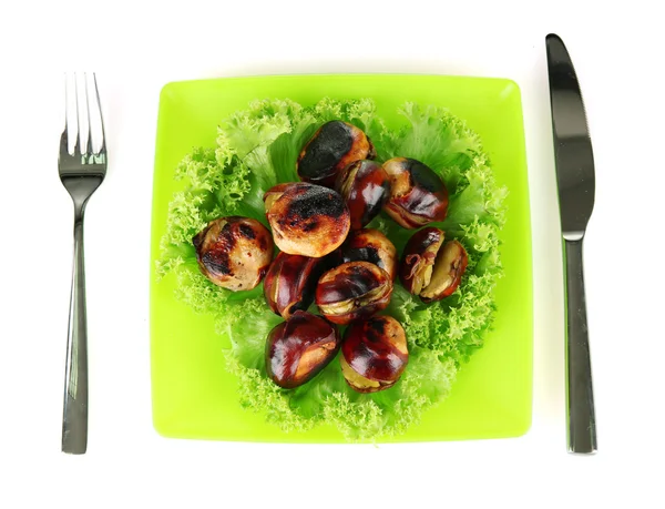 Смажені каштани з салатом в зеленій тарілці з виделкою і ножем ізольовані на білому — стокове фото
