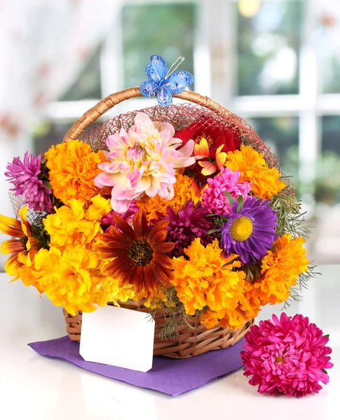 Hermoso ramo de flores brillantes en cesta con nota de papel sobre mesa blanca sobre fondo de ventana —  Fotos de Stock