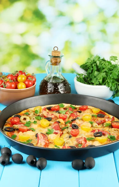 Colorful composition of delicious pizza, vegetables and spices on blue wooden background close-up — Stock Photo, Image