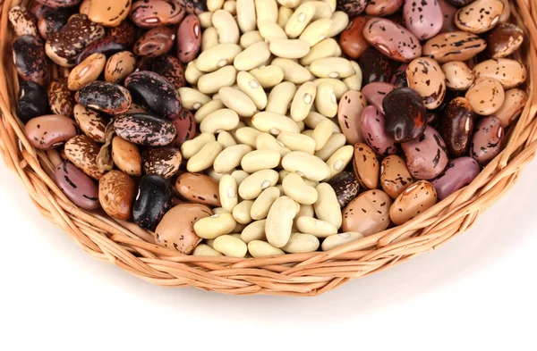 Sprinkled white and brown beans on wicker cradle close-up isolated on white — Stock Photo, Image