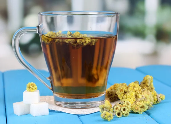 A cup of tea with immortelle on blue wooden table on window background — Stock Photo, Image