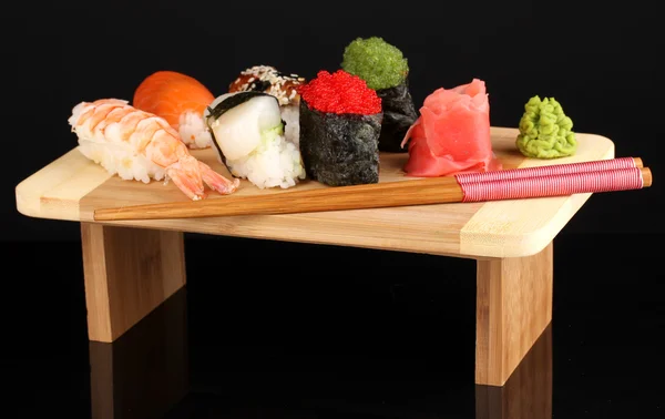 Heerlijke sushi geserveerd op een houten bord geïsoleerd op zwart — Stockfoto