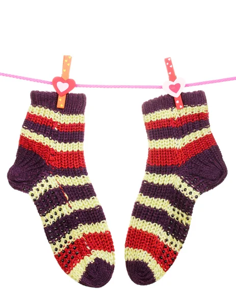 Paar gestrickte gestreifte Socken, die an einem Seil hängen, isoliert auf weiß — Stockfoto