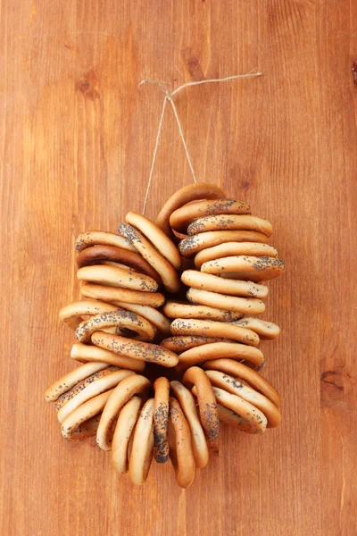 Tasty bagels on rope, on wooden background — Stock Photo, Image