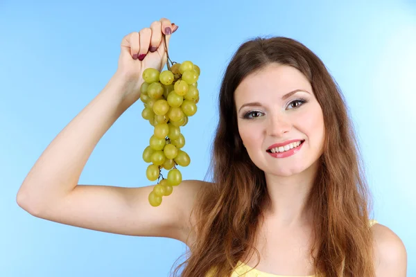 Beautiful woman with grape on blue background — Stock Photo, Image