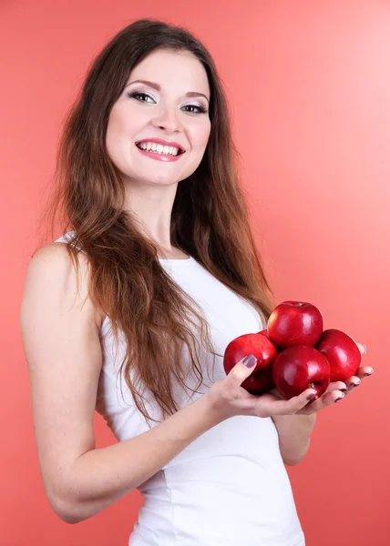 Hermosa mujer con manzanas sobre fondo rosa — Foto de Stock