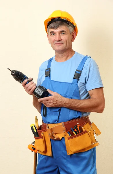 Constructor con taladro sobre fondo de pared — Foto de Stock