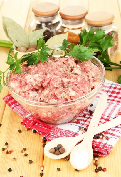 Schüssel mit rohem Hackfleisch mit Gewürzen auf Holztisch — Stockfoto