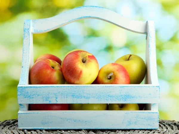 Pommes juteuses dans un panier en bois, sur fond vert — Photo