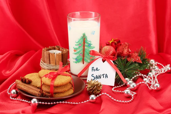 Cookies voor santa: Conceptuele afbeelding van gember koekjes, melk en kerst decoratie op rode achtergrond — Stockfoto