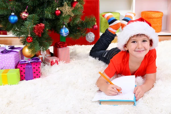 산타 모자에 작은 소년 산타 클로스에 게 편지를 씁니다. — 스톡 사진