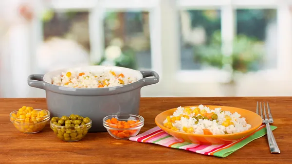 Risotto en maceta gris sobre mesa de madera sobre fondo brillante —  Fotos de Stock