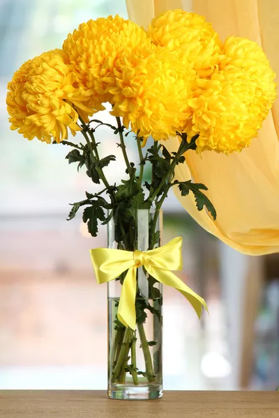 Crisantemos amarillo brillante en jarrón de cristal, sobre mesa de madera — Foto de Stock