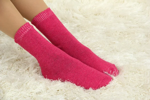 Pernas femininas em meias coloridas no fundo do tapete branco — Fotografia de Stock