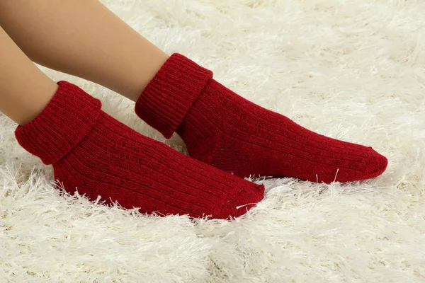 Frauenbeine in bunten Socken auf weißem Teppich-Hintergrund — Stockfoto