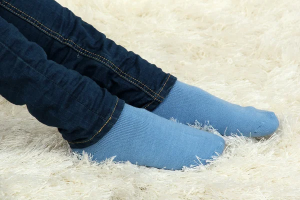 Patas femeninas en calcetines de colores sobre fondo de alfombra blanca — Foto de Stock