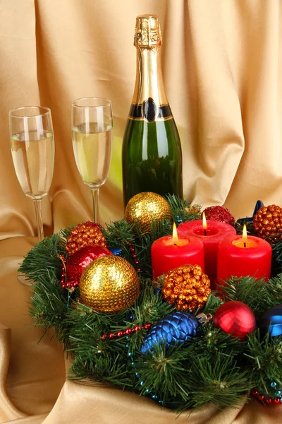 Beautiful Christmas wreath in composition with champagne on gold fabric background — Stock Photo, Image