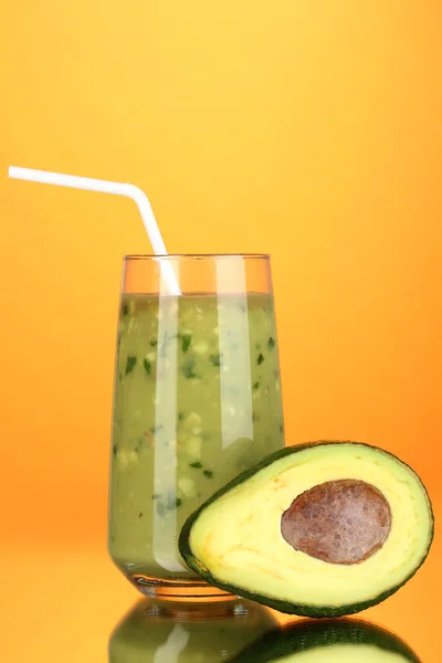 Nuttige verse avocado en halve avocado op oranje achtergrond — Stockfoto