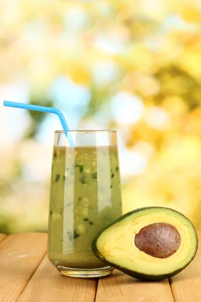 Nützliche frische Avocado und halbe Avocado auf Holztisch vor natürlichem Hintergrund — Stockfoto