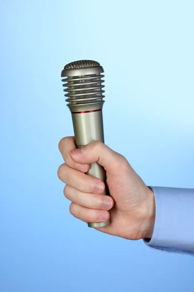 Male hand with microphone on blue background — Stock Photo, Image