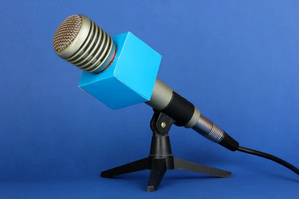 Mavi arka plan üzerinde durmak üstünde mikrofon — Stok fotoğraf