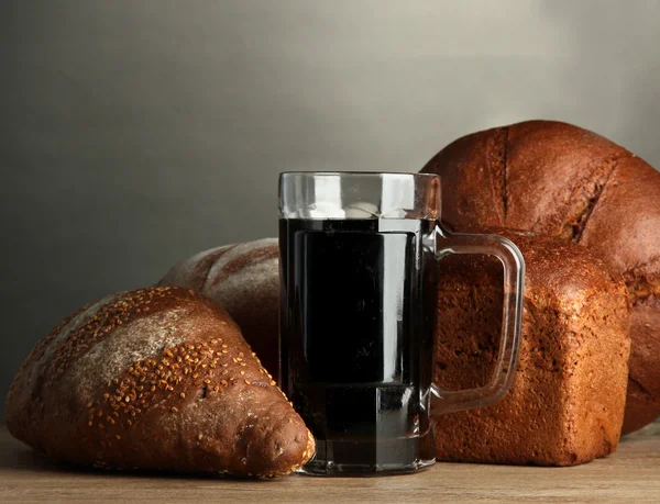 Tankard de pães de kvass e centeio, sobre mesa de madeira sobre fundo cinzento — Fotografia de Stock