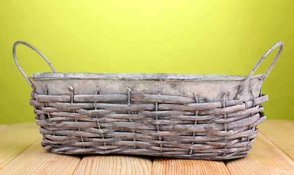 Empty grey basket on wooden table on green background — Stock Photo, Image