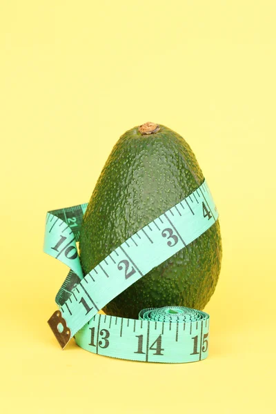 Avocado met meetlint op gele achtergrond — Stockfoto