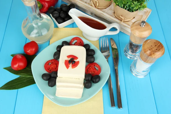 Сыр фета на тарелке со специями и маслом на синем деревянном столе крупным планом — стоковое фото