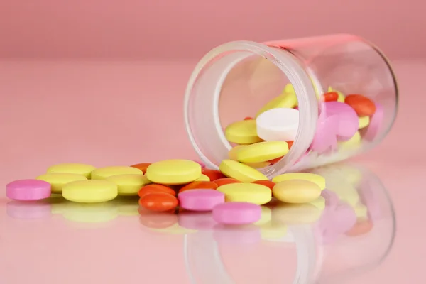 Pills in receptacle on red background — Stock Photo, Image