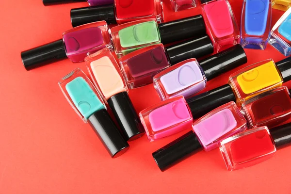 Grupo de esmaltes de uñas brillantes, sobre fondo rojo —  Fotos de Stock