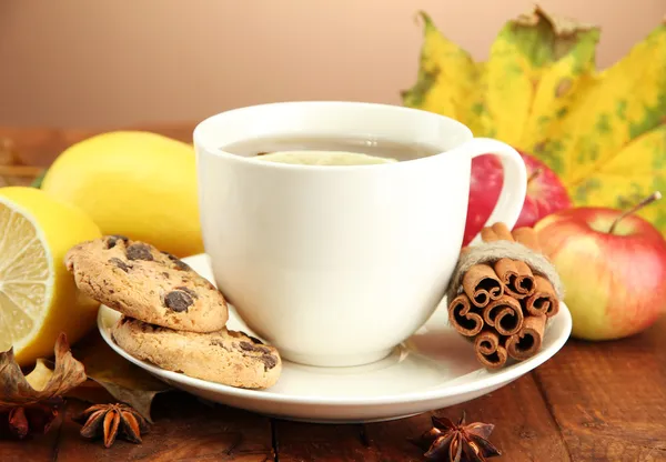 Cup of hot tea and autumn leaves, on brown background — Stock Photo, Image