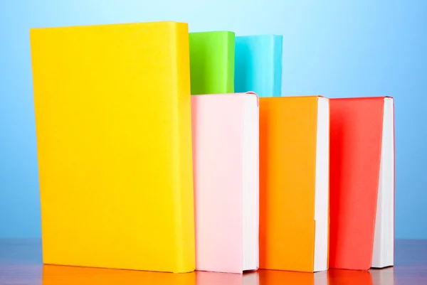 Pila di libri multicolore su sfondo blu — Foto Stock