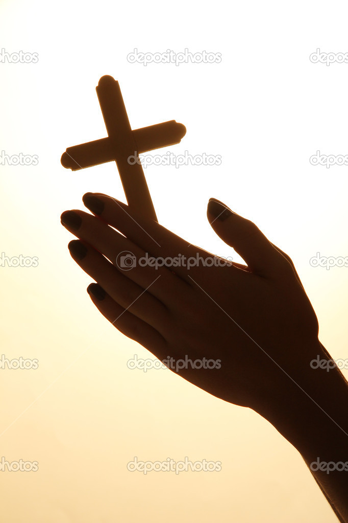 female hands with crucifix, on beige background