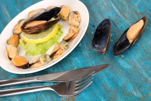 Snack van mosselen en citroen op plaat op blauwe houten tafel — Stockfoto