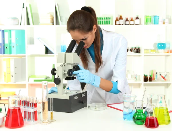 Jonge wetenschapper op zoek naar de Microscoop in laboratorium — Stockfoto