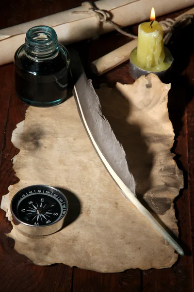 Gamla papper med bläckpenna nära belysning ljus på träbord — Stockfoto