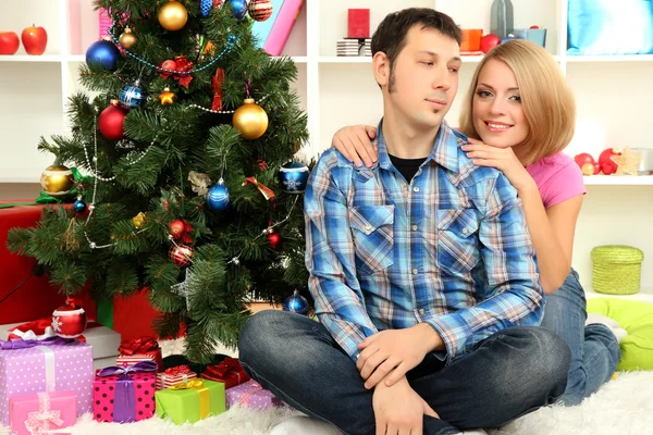 Jovem casal feliz perto de uma árvore de Natal em casa — Fotografia de Stock