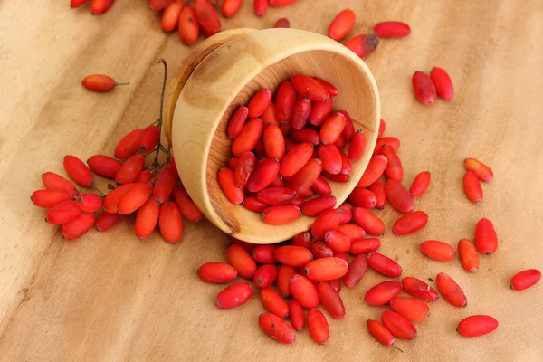 Ripe barberries in wooden bowl, on wooden background — Stock Photo, Image