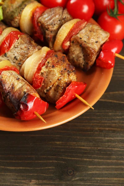 Tasty grilled meat and vegetables on skewer on plate, on wooden table — Stock Photo, Image