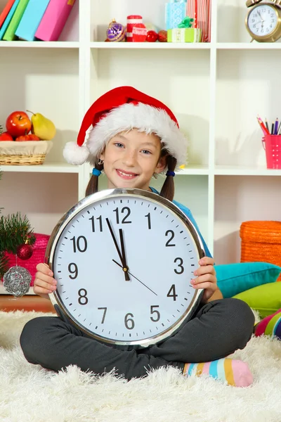 Little girl holding clock near christmas tree Stock Picture