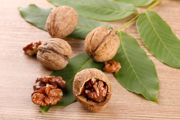 Vlašské ořechy se zelenými listy, na dřevěné pozadí — Stock fotografie