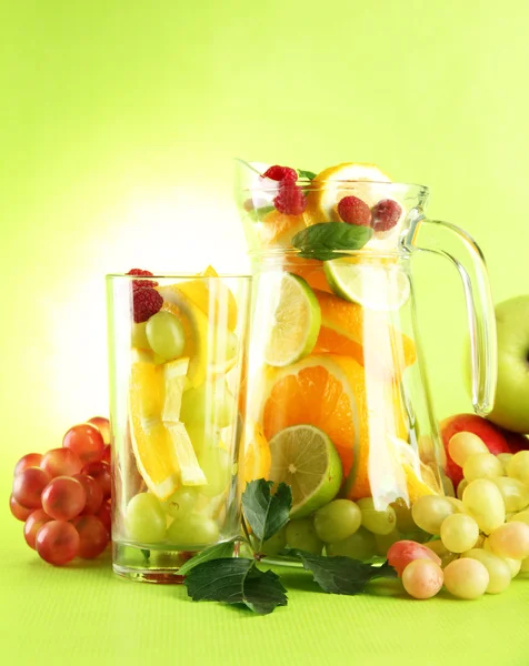 Jar and glass with citrus fruits and raspberries, on green background — Stock Photo, Image