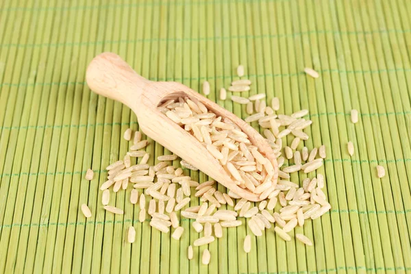 Reis in Holzschaufel auf Bambusmatte — Stockfoto
