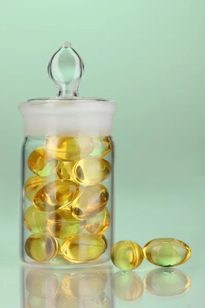 Capsules in receptacle on green background — Stock Photo, Image