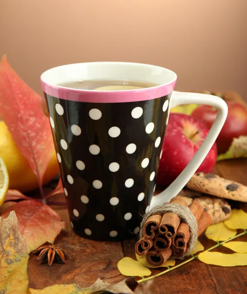 Kahverengi arka planda bir fincan sıcak çay ve sonbahar yaprakları. — Stok fotoğraf
