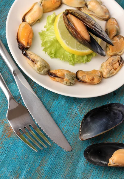 Snack of mussels and lemon on plate on blue wooden table — Stock Photo, Image