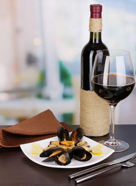 ムール貝のレモンと部屋の背景に木製のテーブルの上の皿の上のワインのスナック — ストック写真