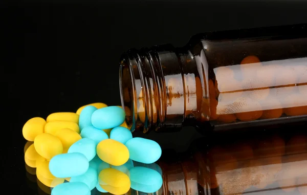 Pills in bottle isolated on black — Stock Photo, Image